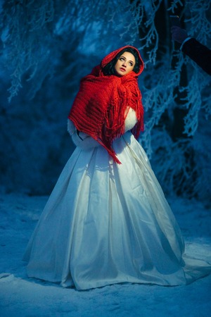 Full-length portrait of the mysterious bride wrapped in the red knitted scarf at night. Winter time.の写真素材
