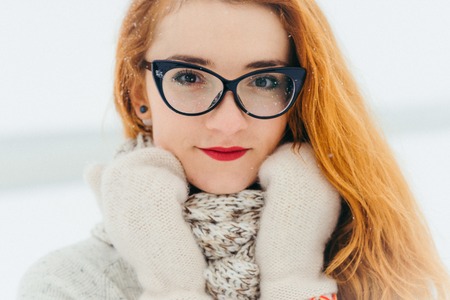 Deep sight of the attractive red head woman wearing glasses. Time-spending in the countryside during the snowfall.の写真素材