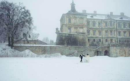 Newlyweds Happy Cheerfully Running Along Snowy Meadow Winter Fun Christmas Wedding New Year Outdoor Full Length.の写真素材