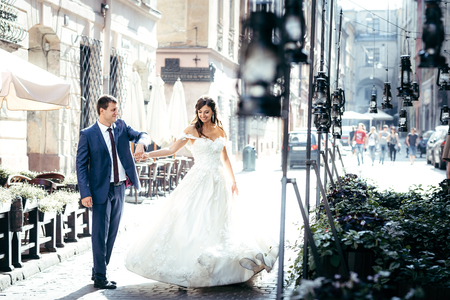 Beautiful newlywed couple is having fun while dancing in the sunny old town street.の写真素材