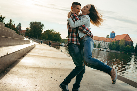 Emotional portrait of the happy smiling couple outdoor. The young man is spinning round his beautiful girlfriend.の写真素材