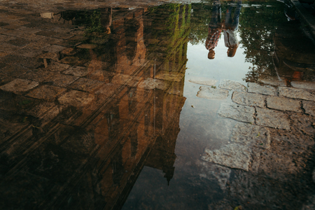 Attractive young loving couple holding hands. The reflection in the puddle. Poland location.の写真素材