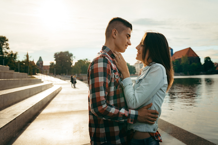 Outdoor portrait. Happy smiling loving ocuple tenderly hugging and talking at the background of the sunset.の写真素材