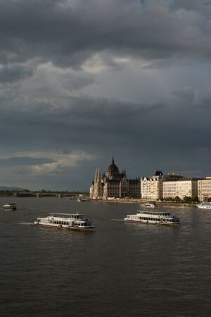 The grey clouds over River Danube full of driving boats. Landscape view of Budapest, Hungary.のeditorial素材