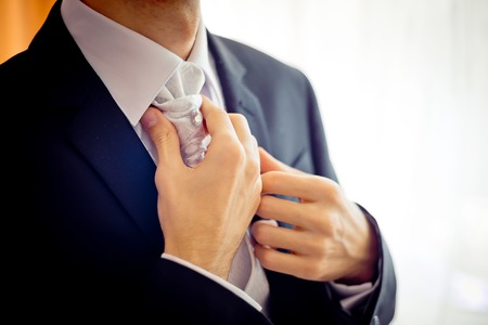 Close-up view of the groom hands correcting the cravat before the wedding ceremony.の写真素材