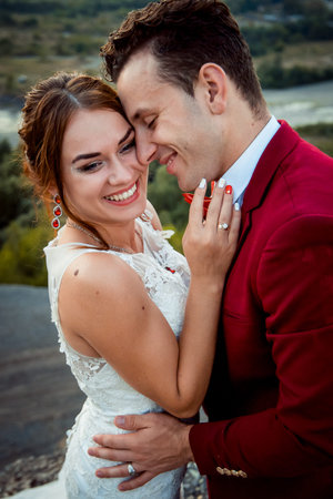 Emotional portrait of the cheerful newlyweds smiling and hugging outdoor.の写真素材