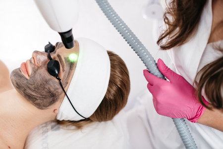 Skin Care and Cosmetics. Beauty Laser Treatment. Woman and Health. Client is receiving the face laser treatment in professional beauty salon.の写真素材