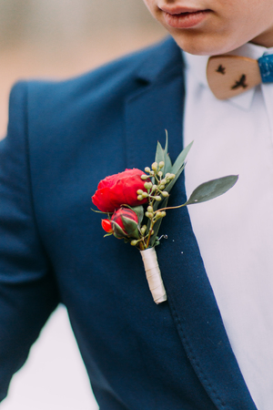 Red boutonniere in the grooms jacket close upの写真素材