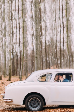 Wedding couple sitting in vintage car. Forest backgroundの写真素材