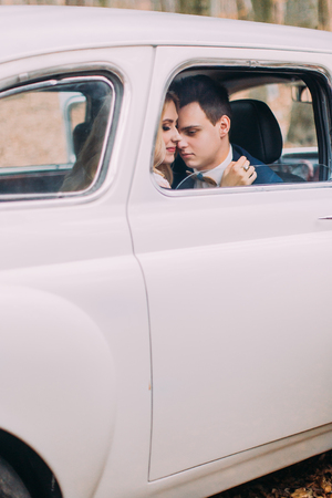 Happy newlyweds in white vintage car close upの写真素材