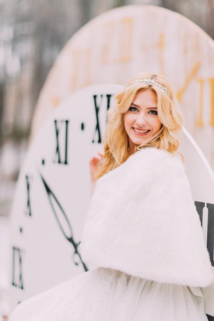 Beautiful blonde bride standing at the big vintage clocks in  autumn forest. Creative wedding decorationsの写真素材