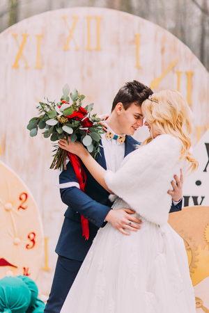 Happy wedding couple softly hugs at the big vintage clocks in  autumn forest. Creative decorationsの写真素材