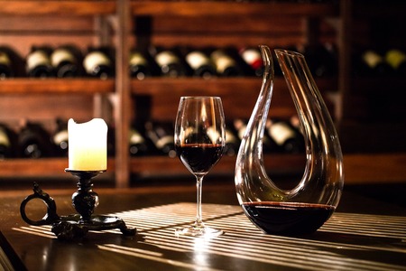 Wine vault. Glass and bottle of wine standing on the table near the candle.の写真素材