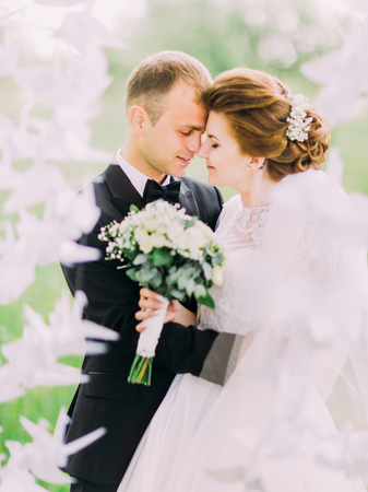 The side portrait of the happy newlyweds behind the paper swans. Forest composition.の写真素材