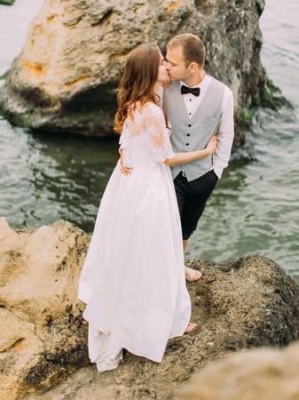 The above outdoor portrait of the kissing newlyweds on the cliff at the background of the sea.の写真素材