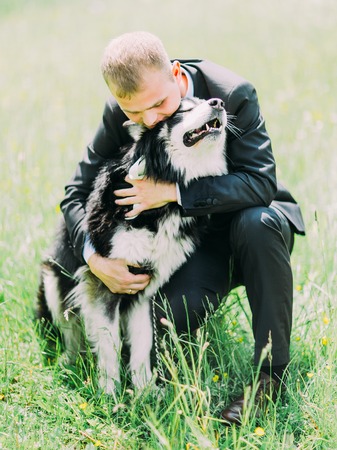 The lovely portrait of the groom hugging the dog in the park.の写真素材