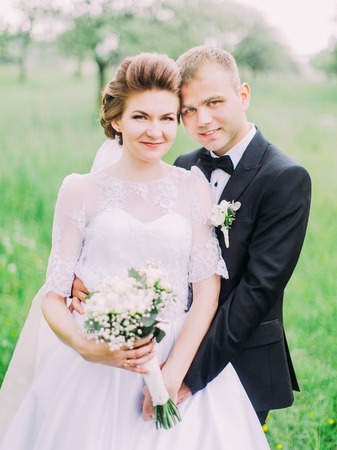 The portrait of the happy newlyweds. Groom is hugging the bride back.の写真素材