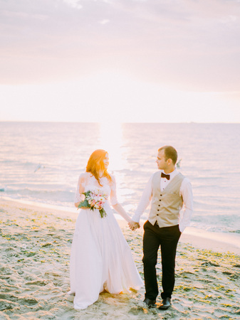 The composition of the sunset in the sea. The newlyweds are holding hands during their walk.の写真素材
