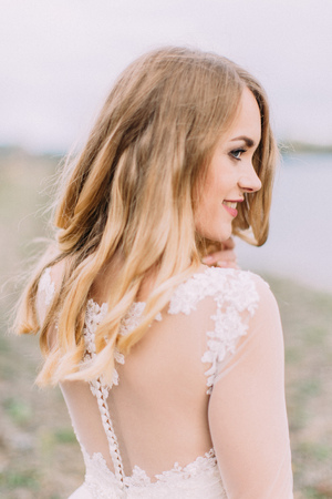 Sensitive outdoor side portrait of the smiling bride at the blurred background of the beach.の写真素材