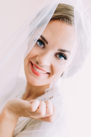 Close-up indoor portrait of the smiling bride with blue eyes.の写真素材