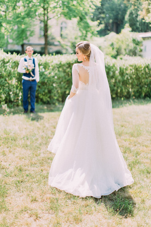The back view of the bride at the blurred background of the groom. Garden location.の写真素材