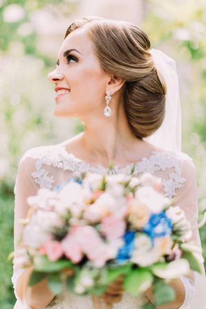 The side portrait of the smiling bride holding the wedding bouquet.の写真素材