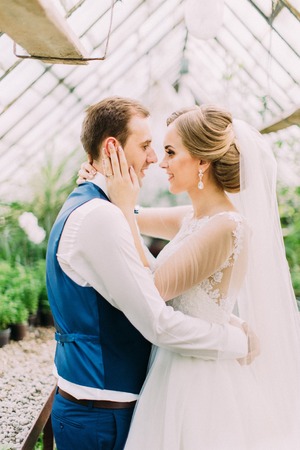 Close-up side portrait of the happy newlyweds. The bride is stroking the cheek of the groom.の写真素材