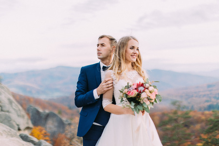 Close-up horizontal portrait of the newlyweds looking at different sides at the blurred background of the yellowed nature.の写真素材