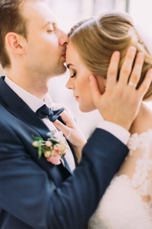 Close-up portrait. Groom is kissing the bride in the forehead.の写真素材