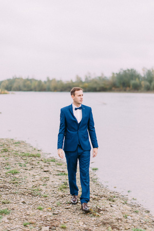 Full-length view of the groom walking along the beach.の写真素材