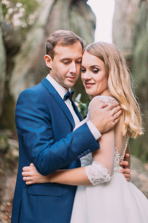 Close-up side portrait of the hugging newlyweds in rocks.の写真素材