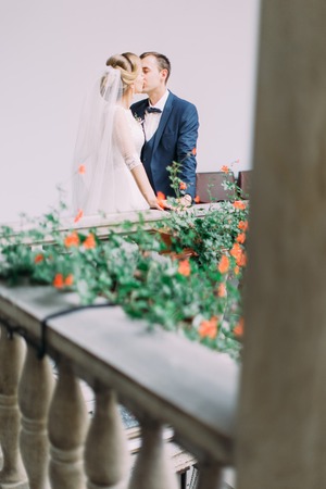 Lovely balcony with flowers and kissing newlywed couple on it.の写真素材