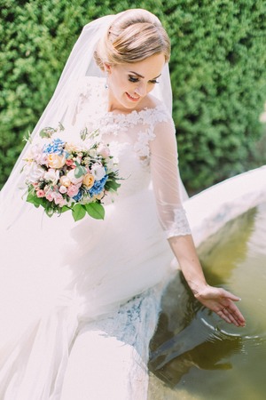 Close-up side view of the pretty bride playing with the water in fountain.の写真素材