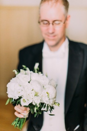 Beautiful wedding bouquet of white peonies in the hands of the groom.の写真素材