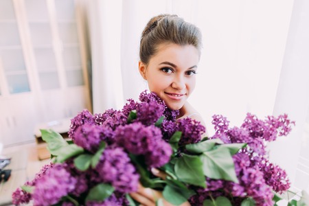 A huge bouquet of lilac in the hands of the smiling pretty bride.の写真素材