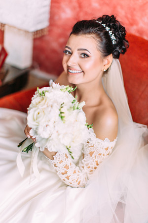 Portrait of the charming smiling bride holding the white wedding bouquet of roses.の写真素材