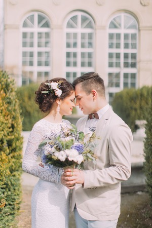 Happy young newlyweds embracing near the old beige house with columns and big vintage windows. Romantic wedding in Parisの写真素材