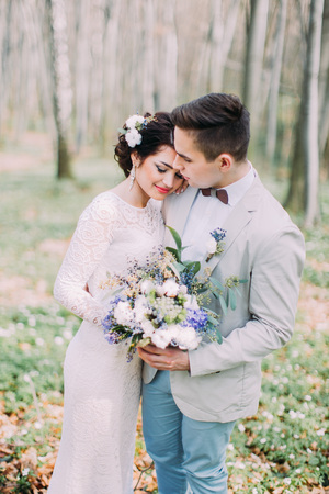 Beautiful wedding couple with bridal bouquet of spring flowers in hands at the green parkの写真素材