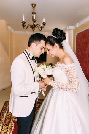 The half-length portrait of the newlyweds holding wedding bouquet while standing head-to-head.の写真素材