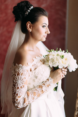 Half-length side portrait of the beautiful bride holding the wedding bouquet.の写真素材