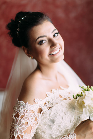 The smiling bride with the wedding bouquet of white roses. Close-up portrait.の写真素材