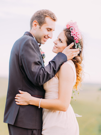 The outdoor portrait of the smiling newlyweds. The groom is stroking the cheek of the bride.の写真素材