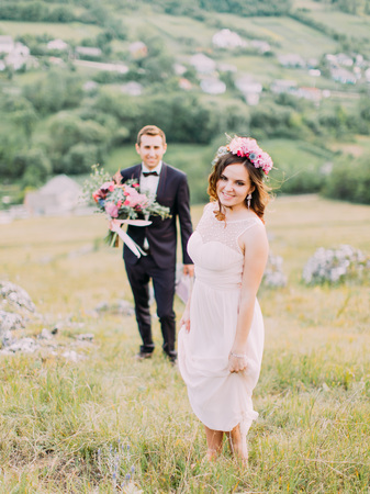 The close-up view of the bride standing in the front of the blurred groom with the wedding bouquet.の写真素材