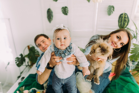 The close-up portrait of the baby held by the father while the mother is holding the rabbit. Home composition.の写真素材