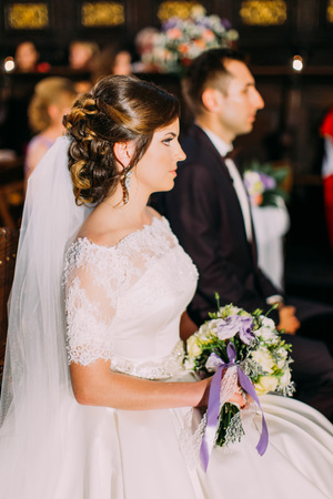 Wedding ceremony. Side view of the newlyweds. Bride holds the wedding bouquet.の写真素材