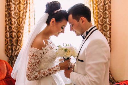 Happy newlyweds are holding the wedding bouquet while standing head-to-head.の写真素材