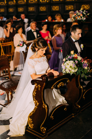 The full-length view of the newlyweds standing on their knees while praying.の写真素材