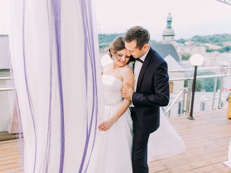 The sensitive portrait of the groom hugging the bride back on the balcony.の写真素材
