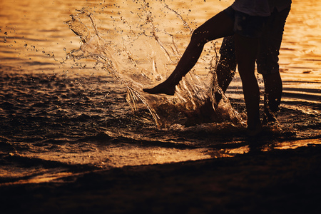 people play their feet in the water at sunsetの写真素材