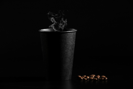 close-up. A black glass of hot coffee with scattered coffee beans on a black background.の写真素材